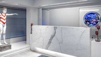 A reception area with a marble reception desk, a statue, a blue aquarium, and a blue rug.