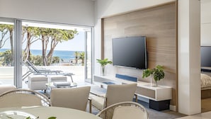 Un salon moderne doté d’un grand téléviseur, de sièges confortables, d’un coin repas et offrant une vue sur l’océan.