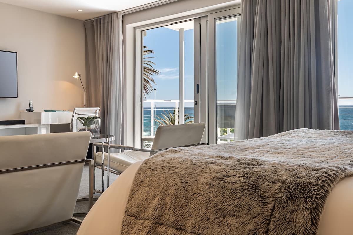 A hotel room with a large bed, a desk, and a view of the ocean.