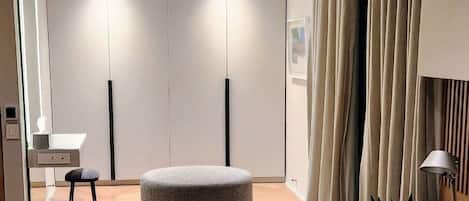 Une chambre moderne avec un plancher en bois, un pouf gris, un bureau avec une chaise et une armoire à portes coulissantes.