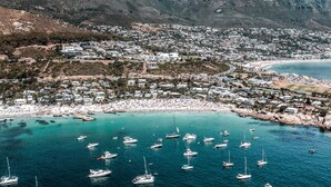 Une ville côtière avec une plage, des bateaux et des montagnes en arrière-plan.