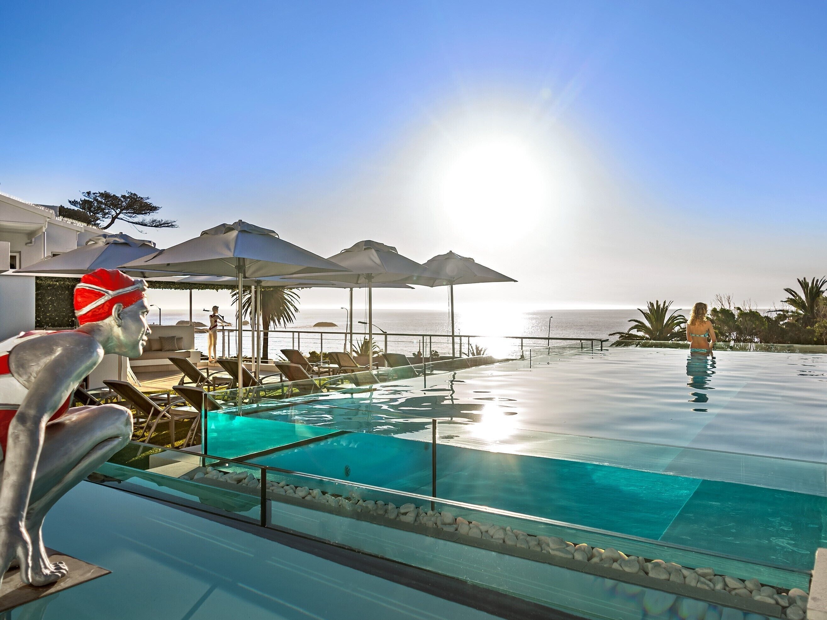 A pool area with clear blue water, lounge chairs, and umbrellas.