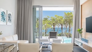 Une chambre d’hôtel moderne dotée d’un balcon, d’un canapé, de deux fauteuils, d’une télévision et offrant une vue sur la piscine.