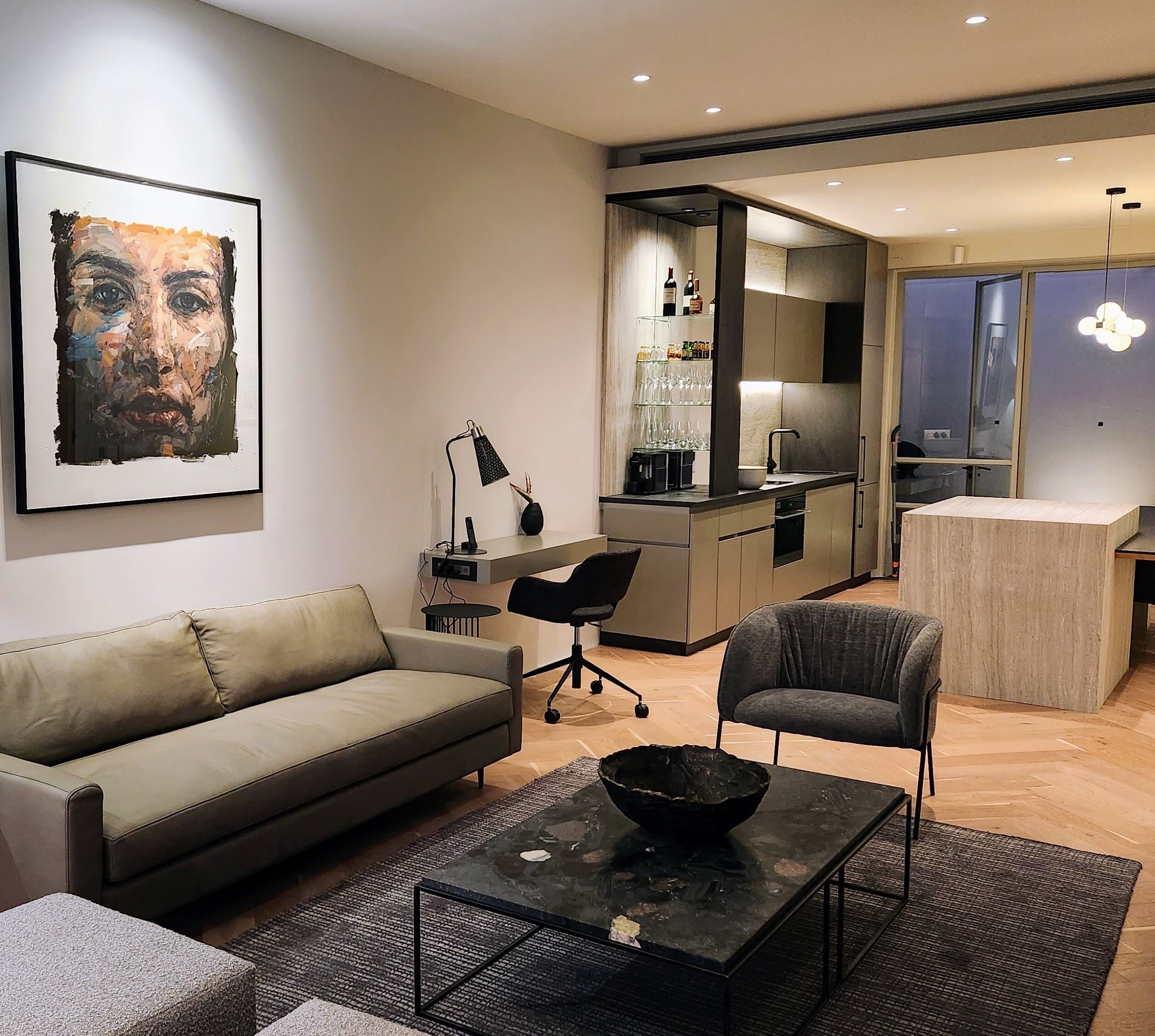 Ein modernes Wohnzimmer mit einer Couch, einem Sessel, einem Couchtisch und einem Gemälde an der Wand.