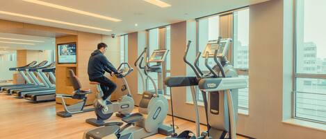 Un gimnasio con cintas de correr, bicicletas estáticas y máquinas elípticas.