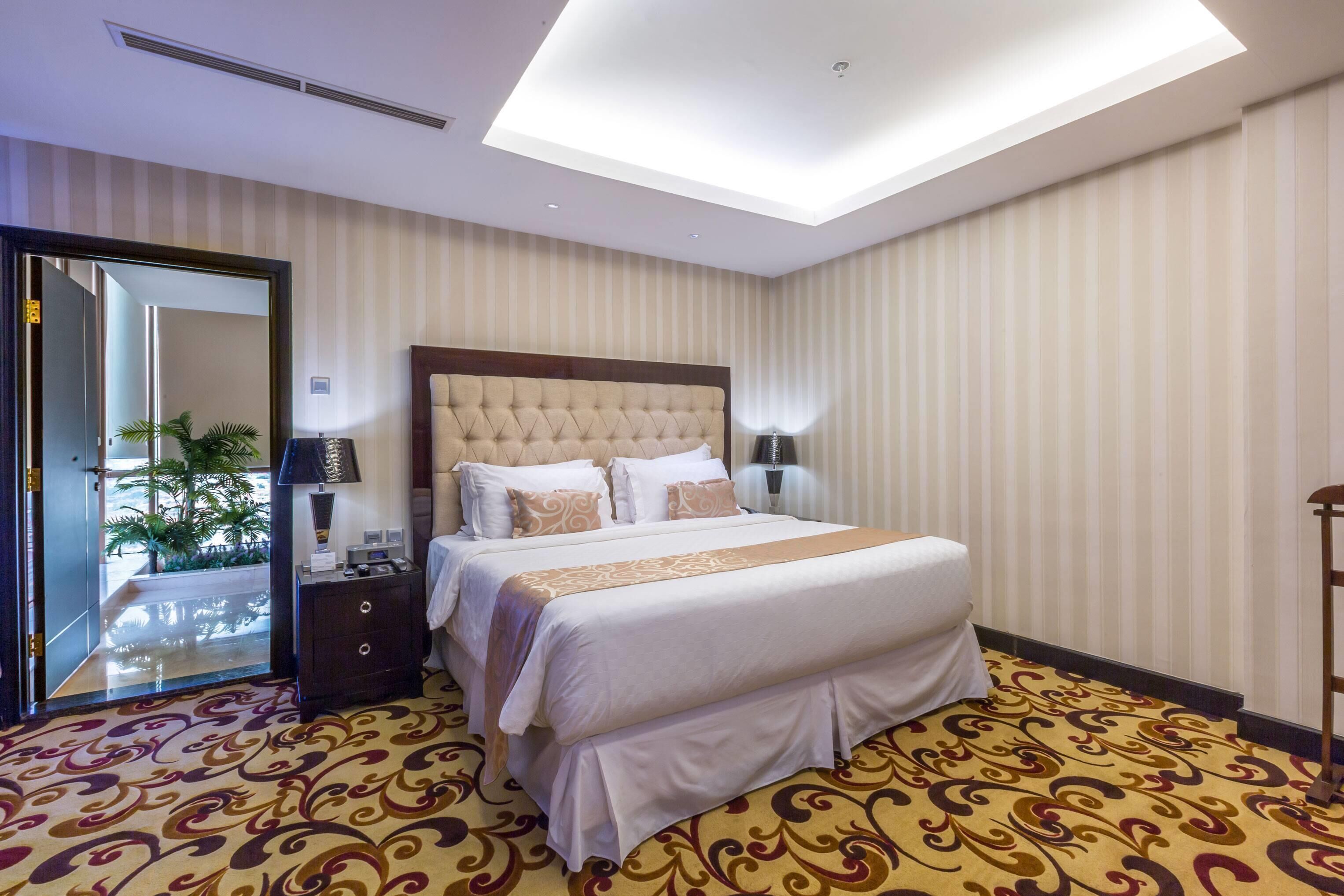 Une chambre d’hôtel avec un grand lit, une table de chevet, une lampe et une vue sur l’extérieur par une porte.