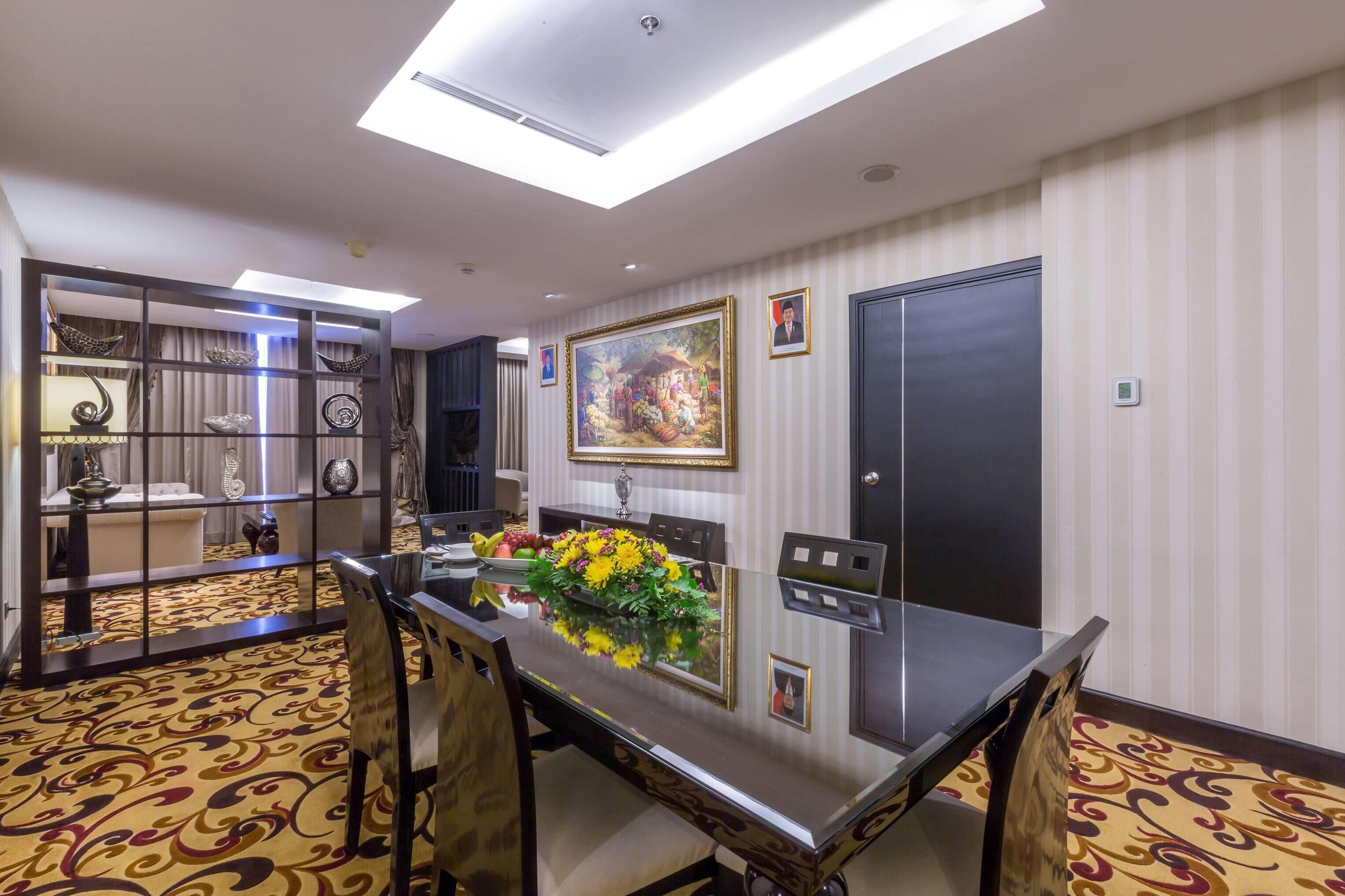Un espace repas moderne avec une table à plateau en verre, des chaises et un élément décoratif central.