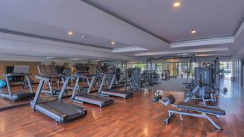 Un gimnasio amplio con cintas de correr, máquinas de pesas y un espejo grande.