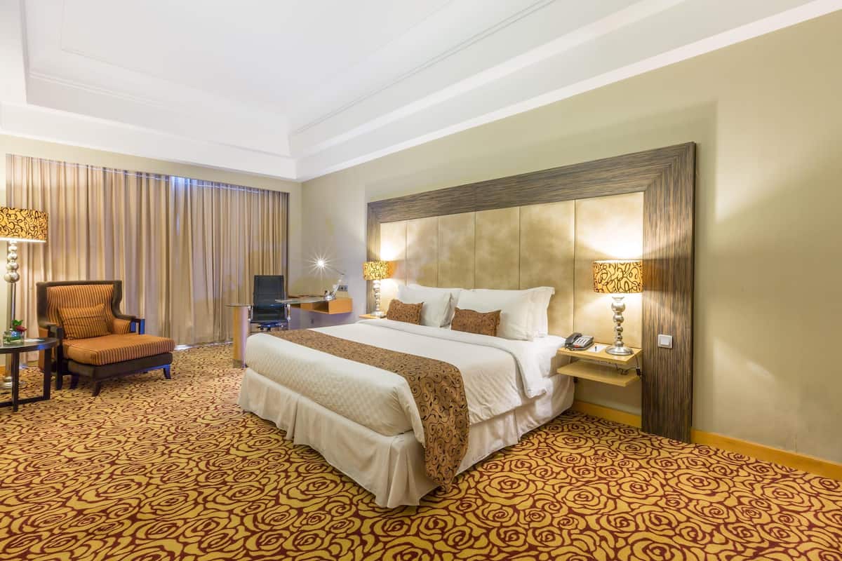 Una habitación de hotel con una cama grande, una silla, un escritorio y un televisor.