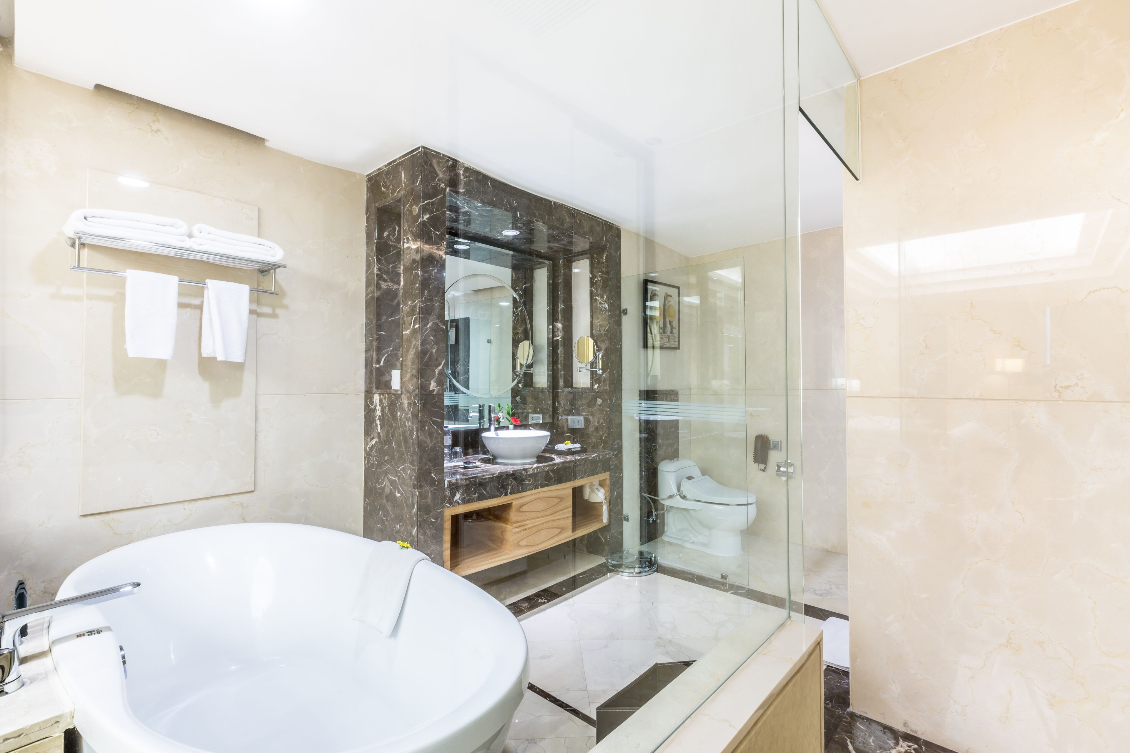 A modern bathroom with a large freestanding bathtub, a glass-enclosed shower, and a marble vanity.