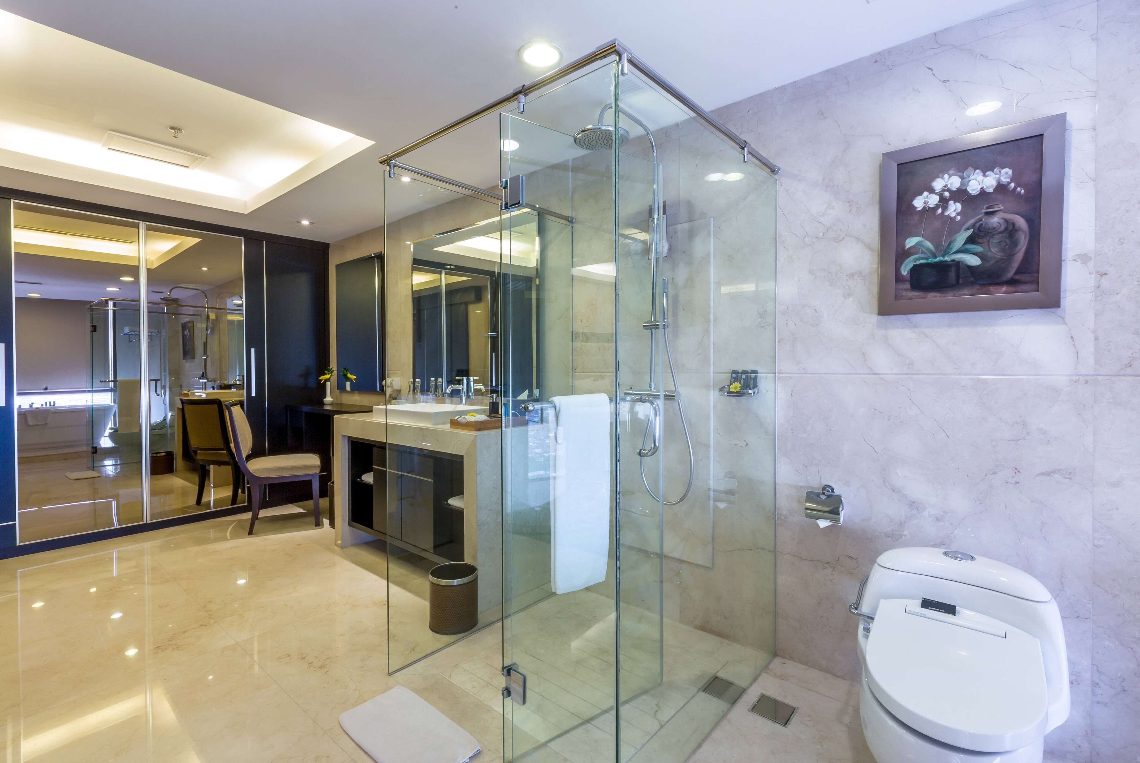 Ein modernes Badezimmer mit einer Glasdusche, einer Toilette und einem Waschbecken mit Spiegel.