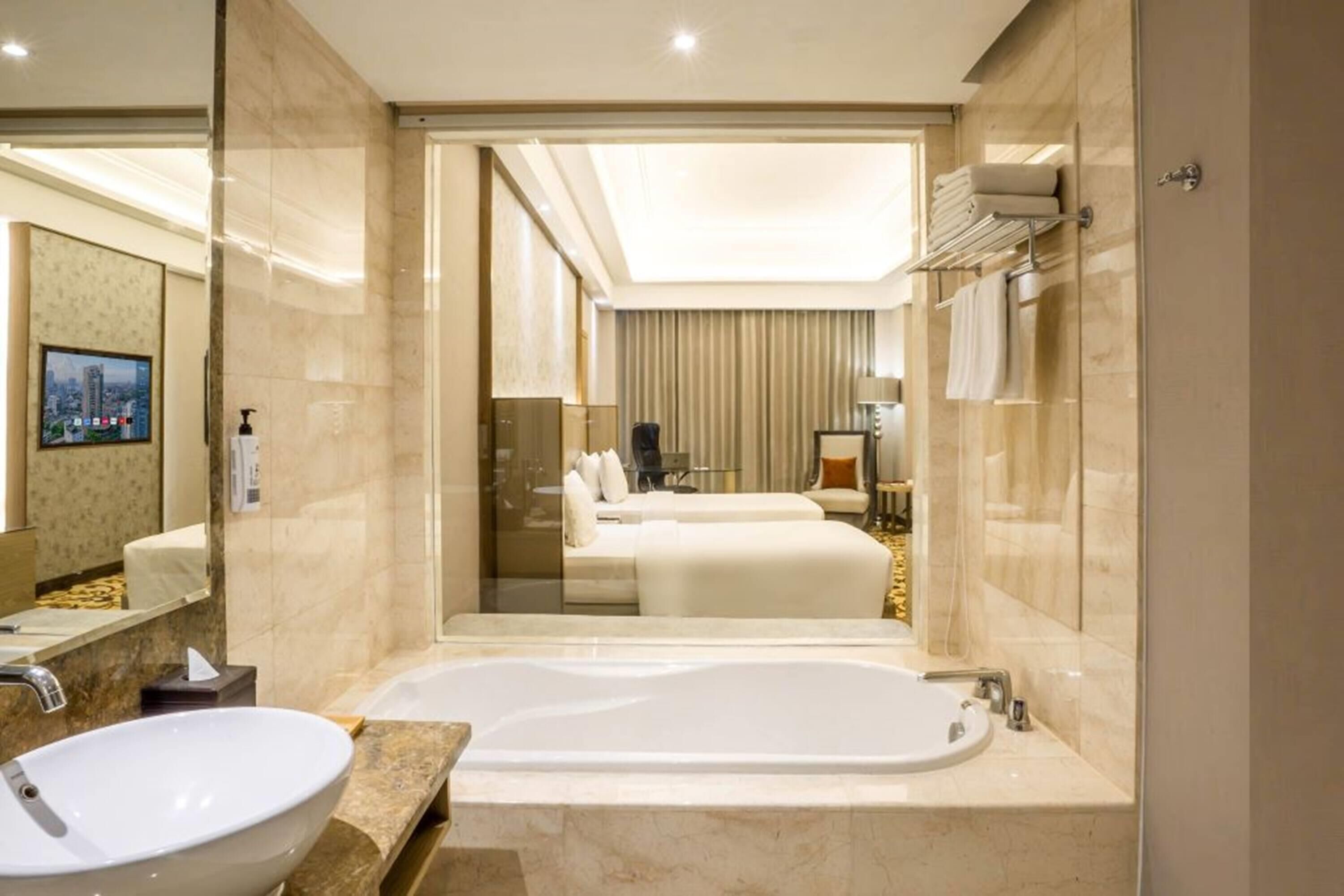 A modern hotel bathroom with a large bathtub, a round sink, and a mirror.