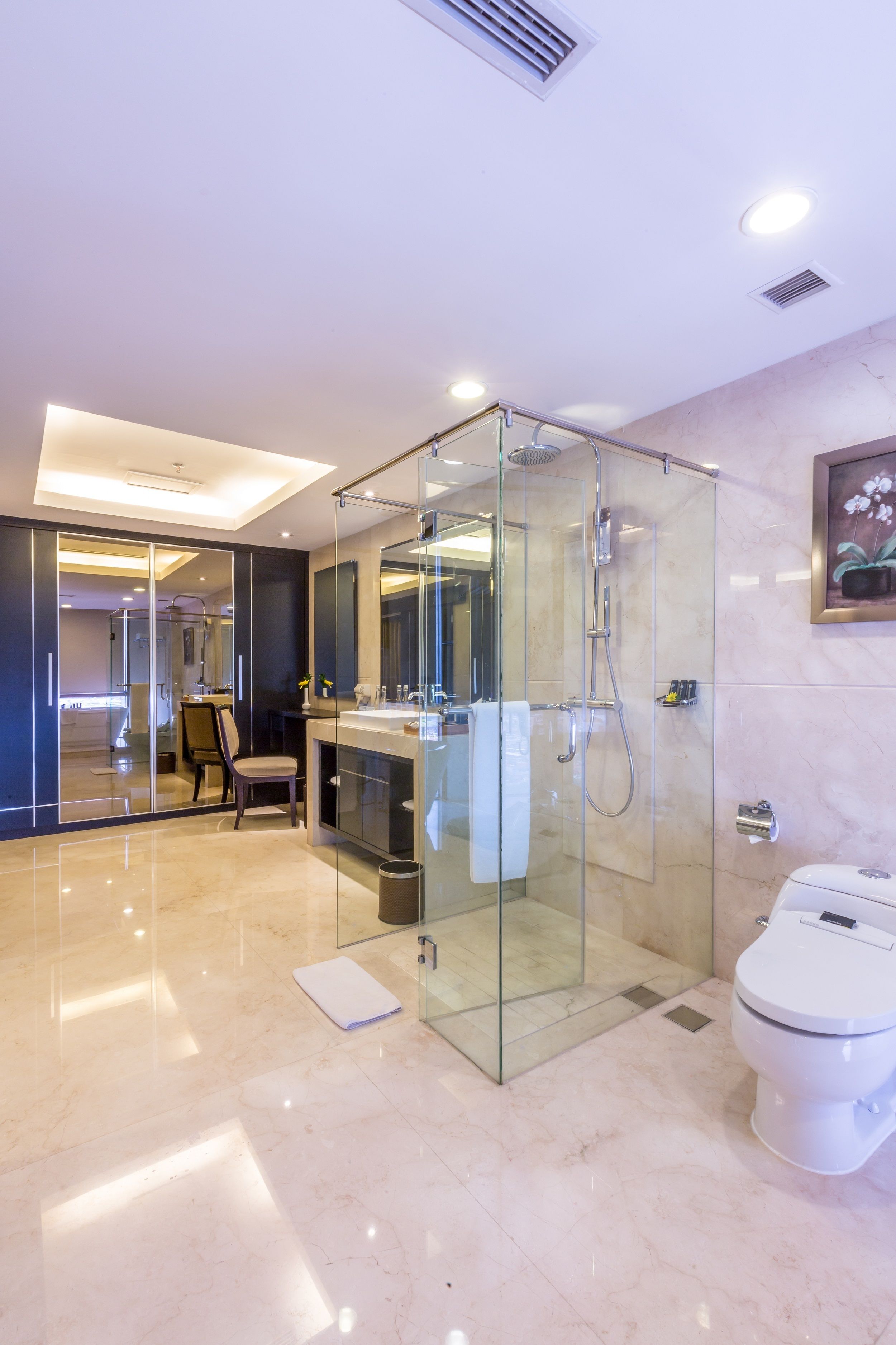A modern bathroom with a glass-enclosed shower, a toilet, and a sink with a mirror.
