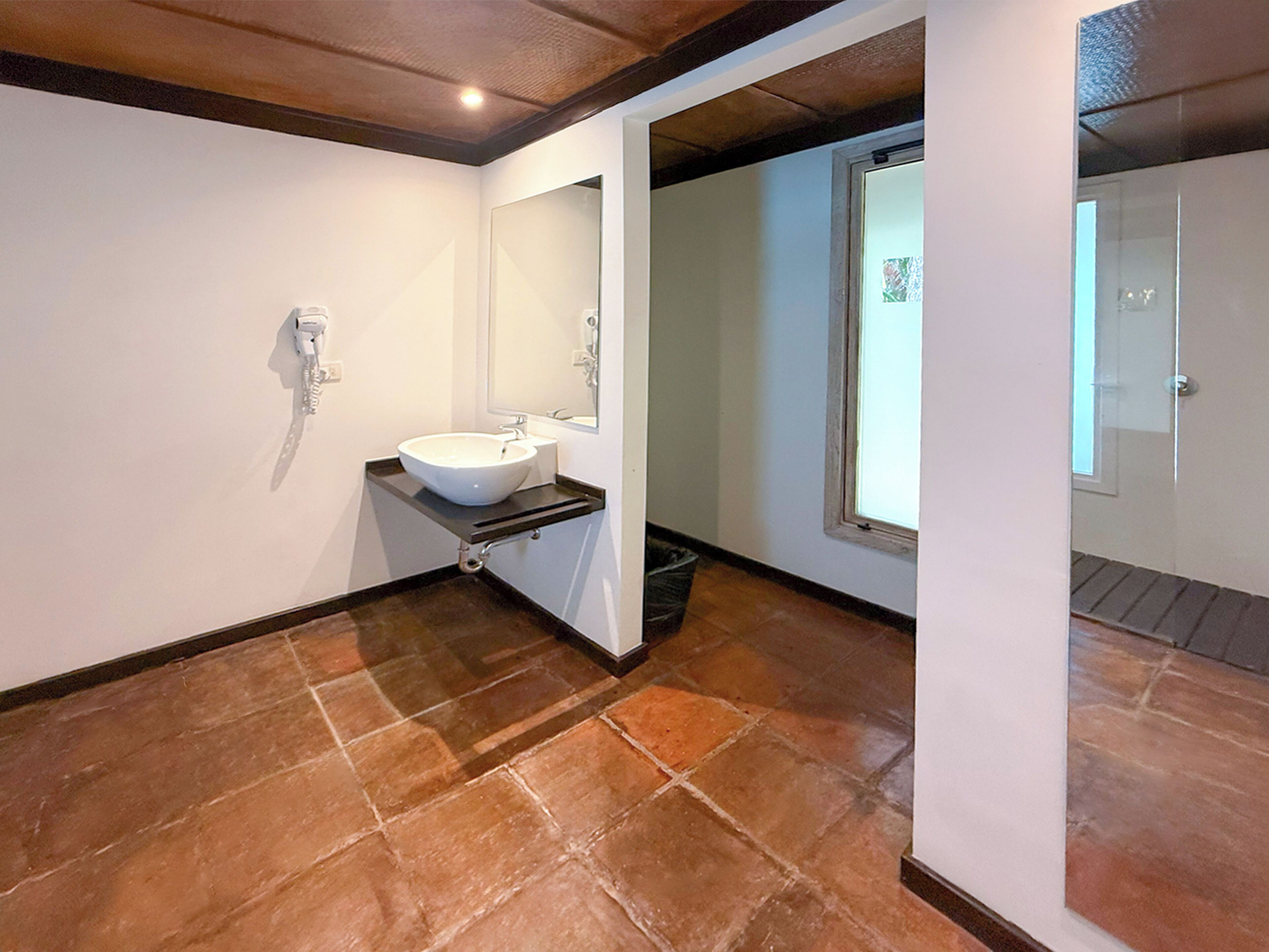 Un baño con un lavabo blanco, un espejo y una ventana.