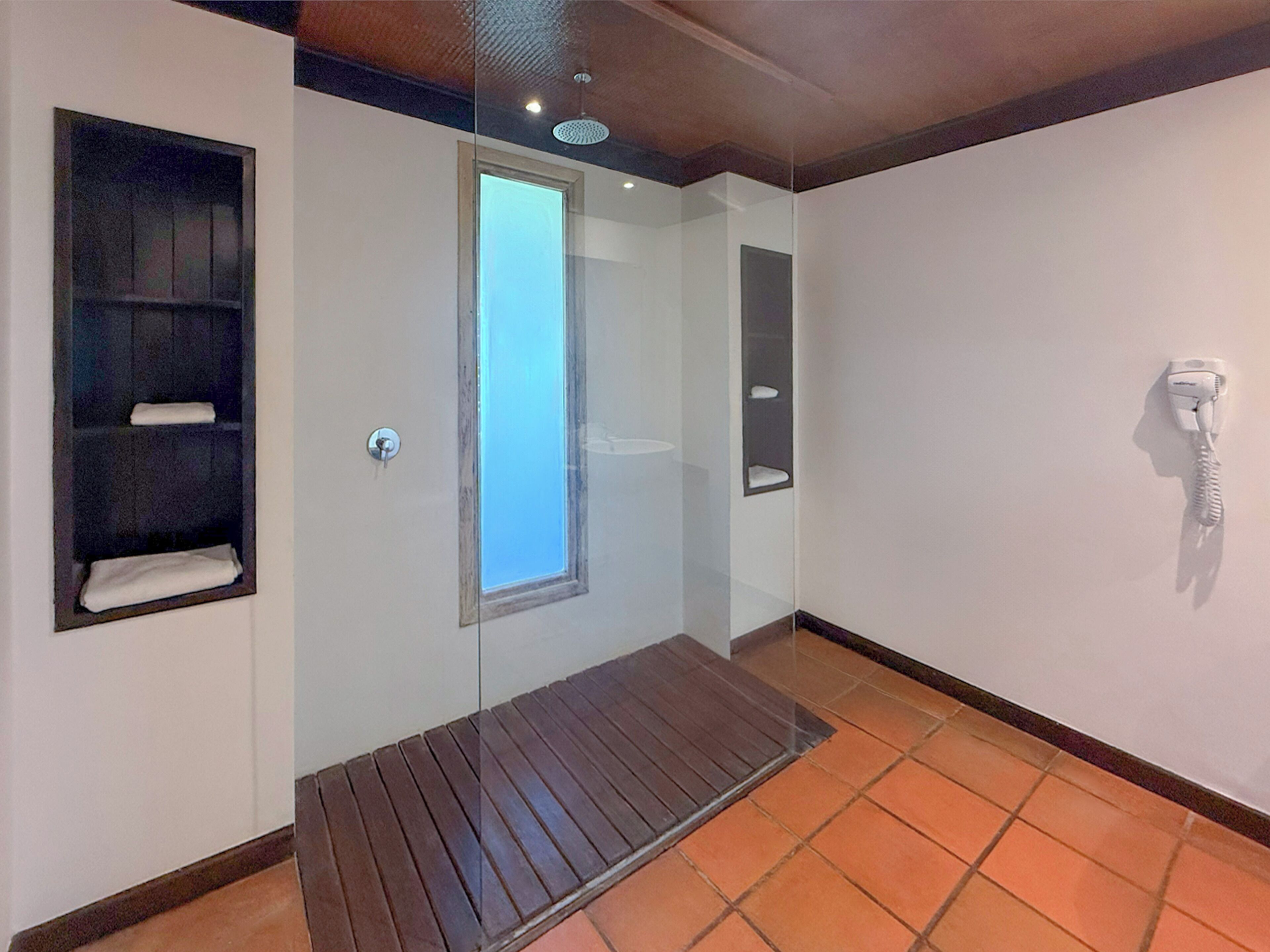 Een badkamer met een douche, een handdoekhouder, een toilet en een telefoon.