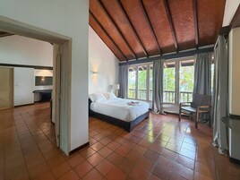 Un dormitorio espacioso con una cama grande, un escritorio y vistas a zonas verdes a través de las ventanas.