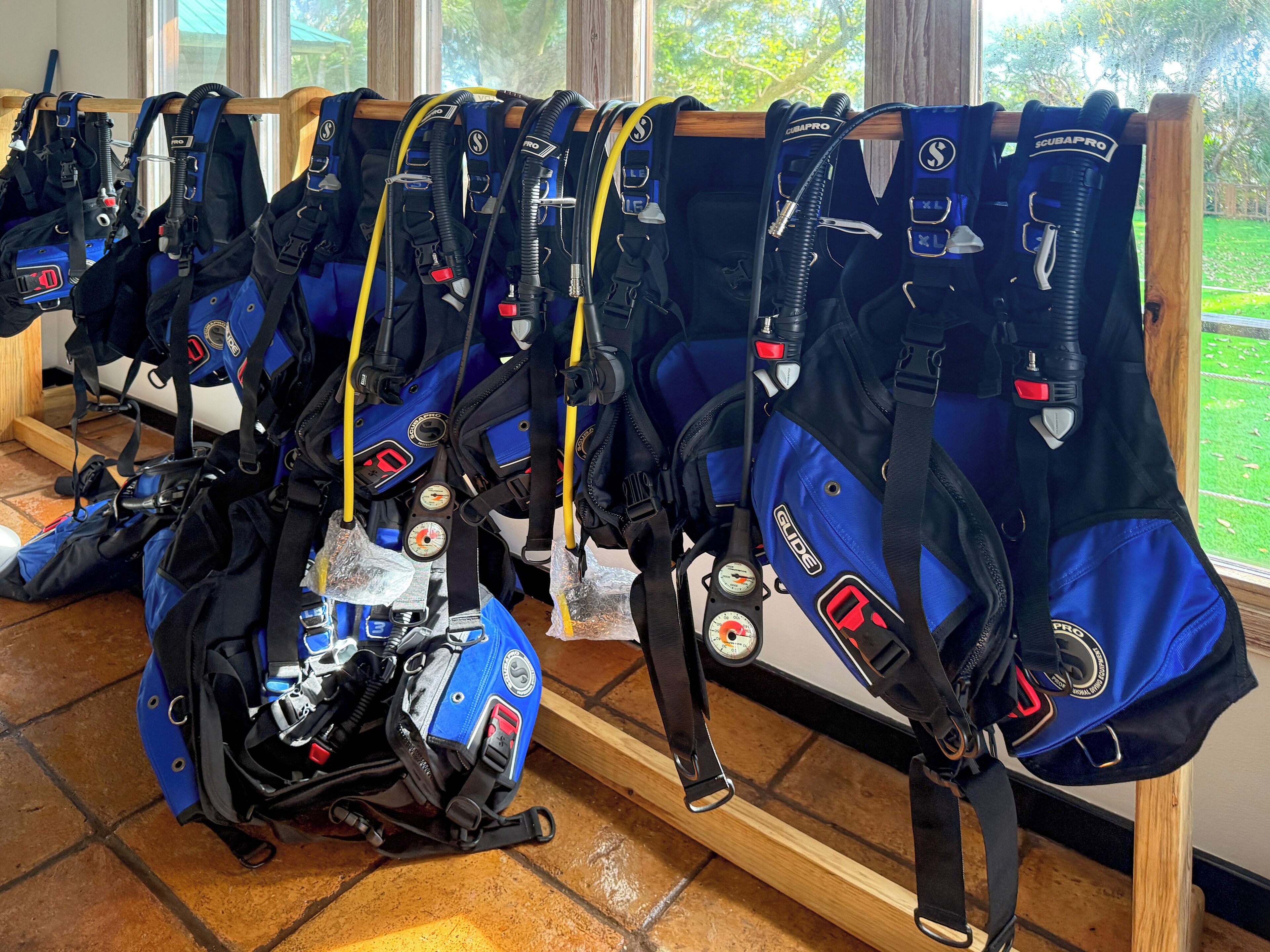 Una hilera de equipo de buceo azul y negro colgado en un estante de madera.