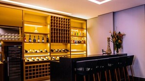 A modern bar area with a wine rack, bar stools, and a refrigerator. - Fratele Business (Patos de Minas)