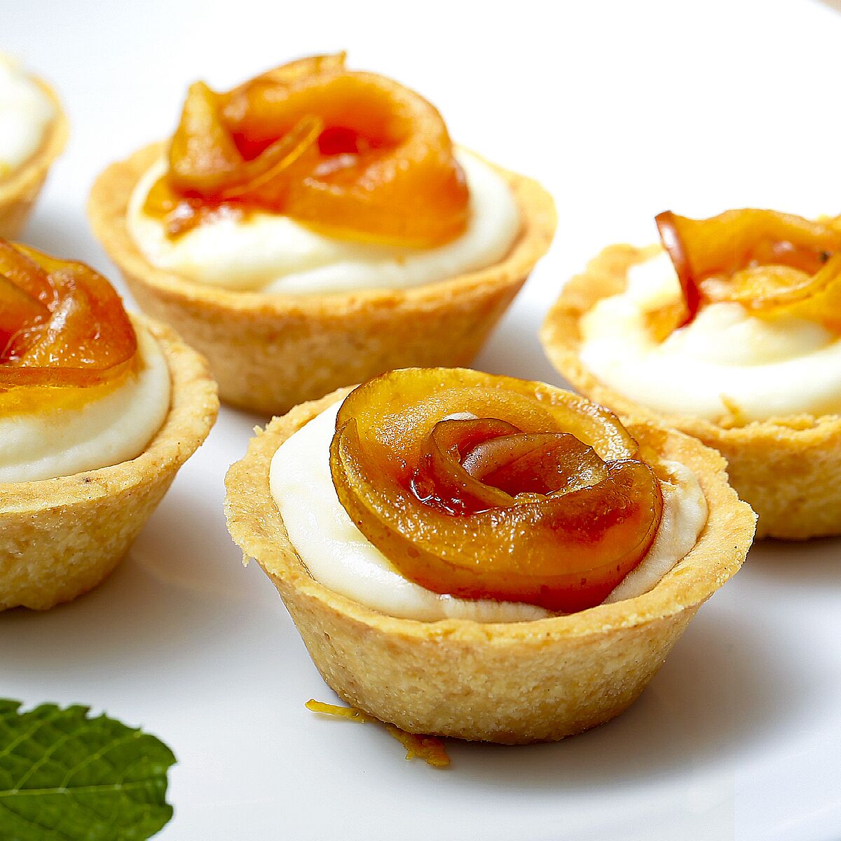 Eine Nahaufnahme von Mini-Törtchen mit cremiger Füllung und karamellisiertem Obst.