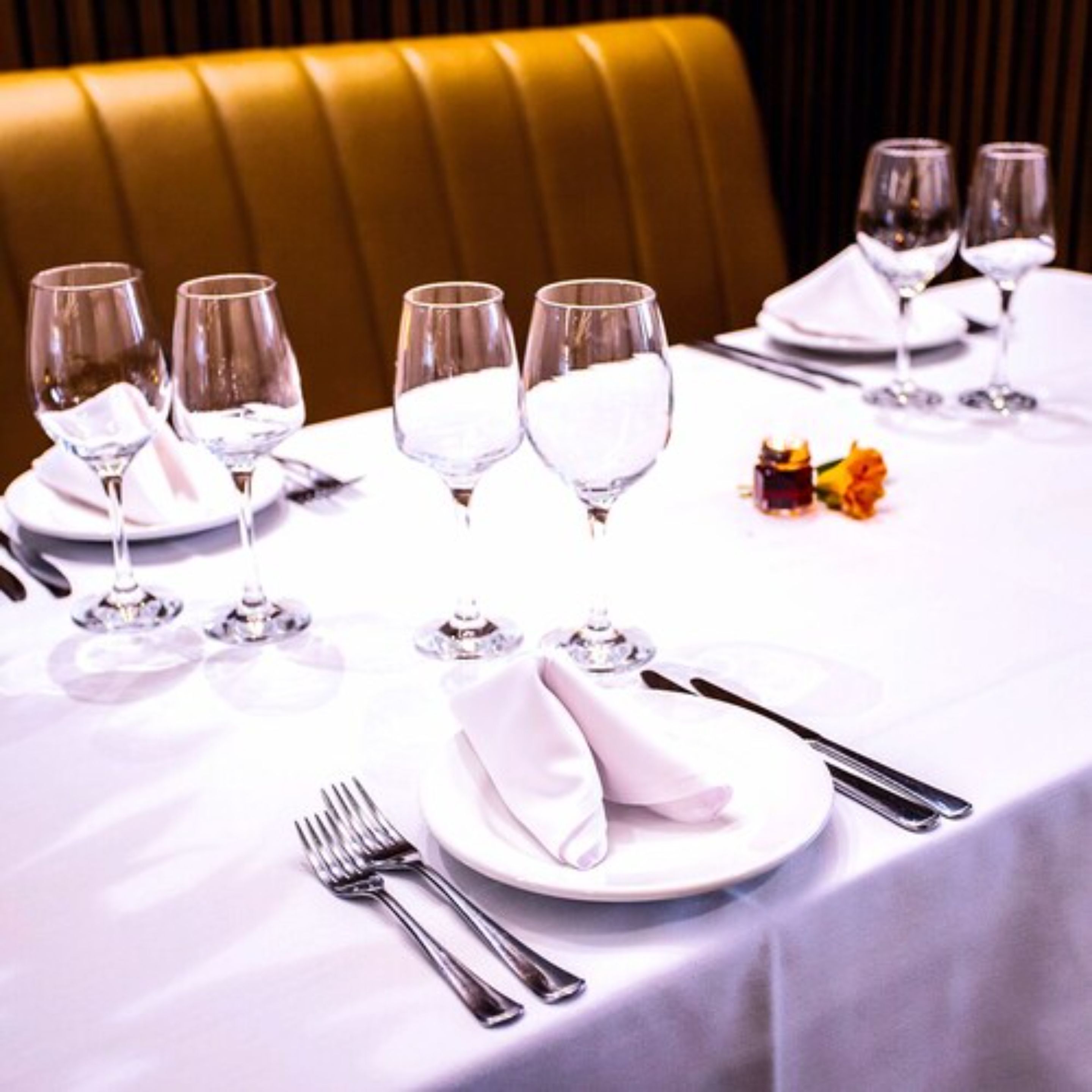 A table set for dining with multiple wine glasses, plates, and cutlery.