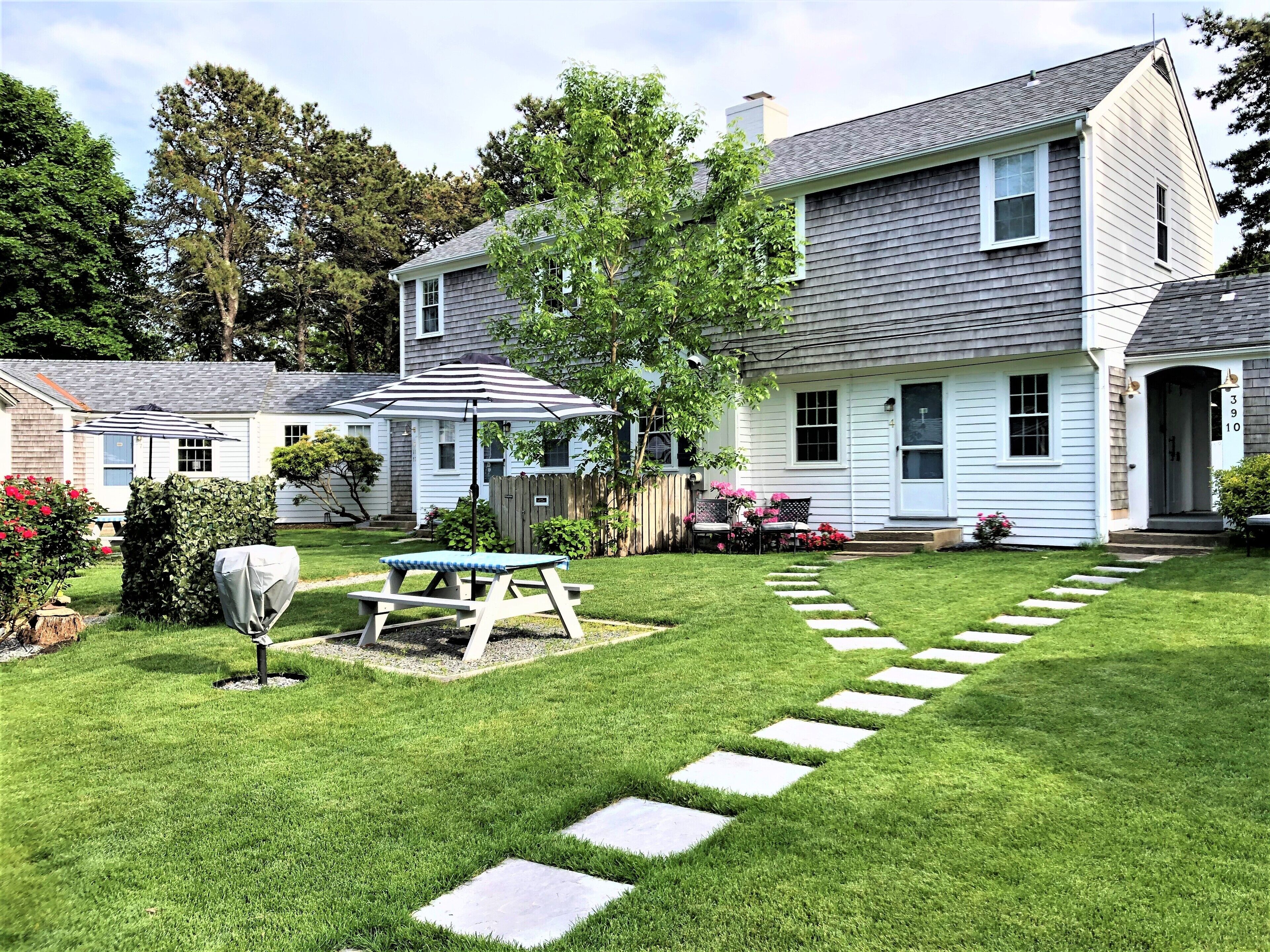 A residential house with a well-maintained lawn, a picnic table, and a covered patio area.