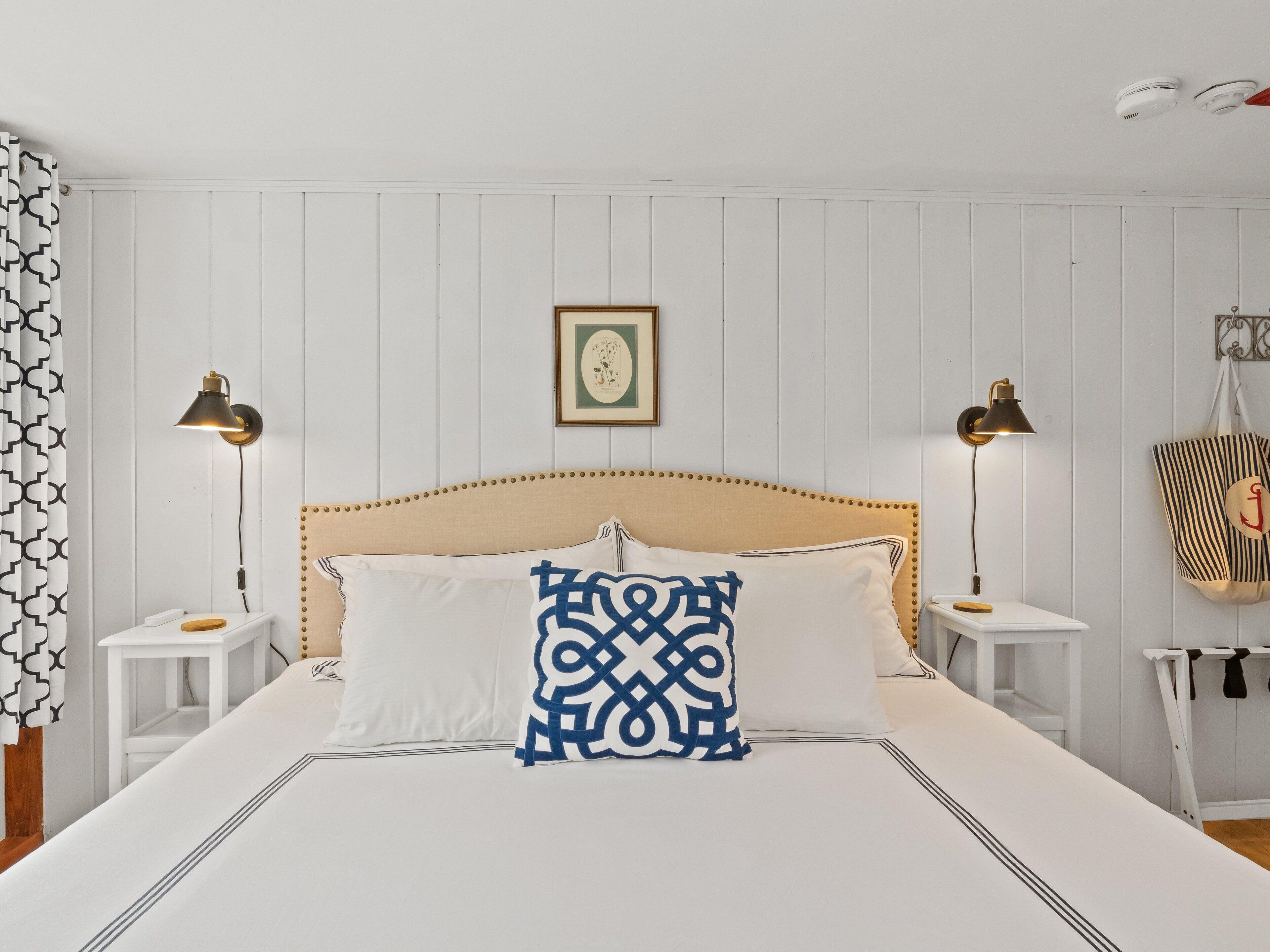A neatly arranged bedroom with a bed, two bedside tables, and a hanging chair.