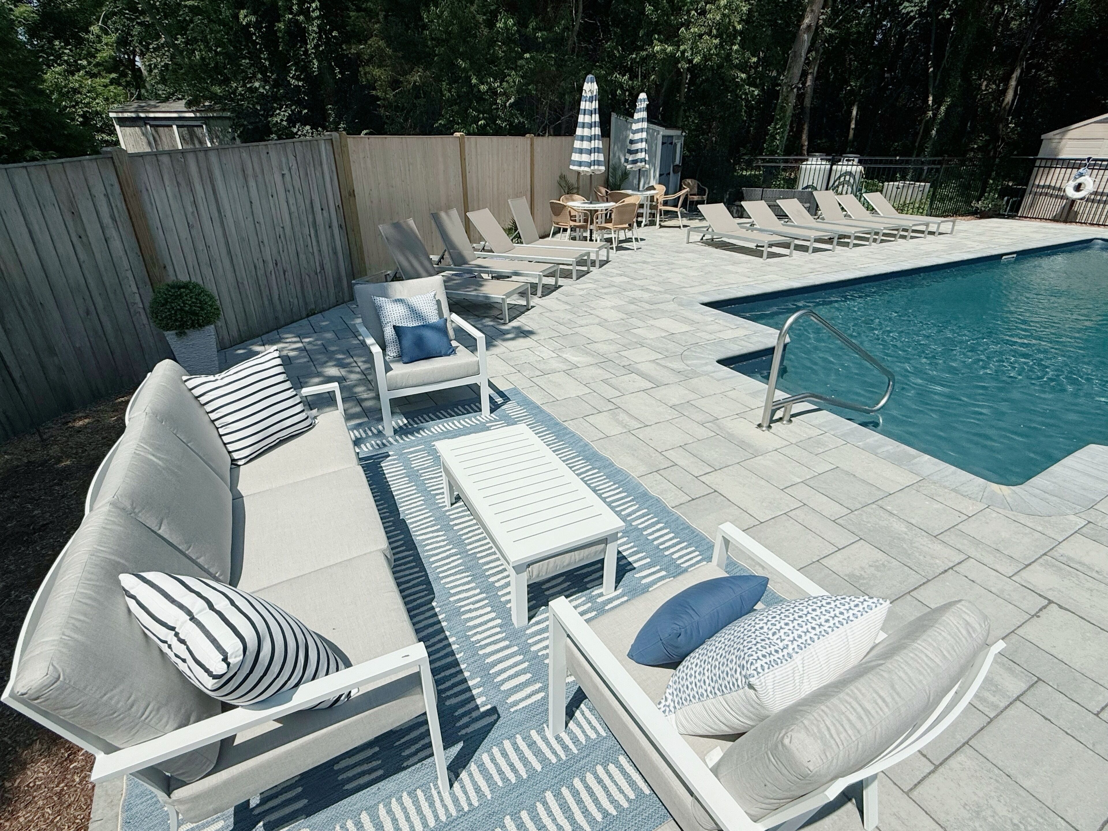 A poolside area with lounge chairs, a small pool, and a wooden fence.