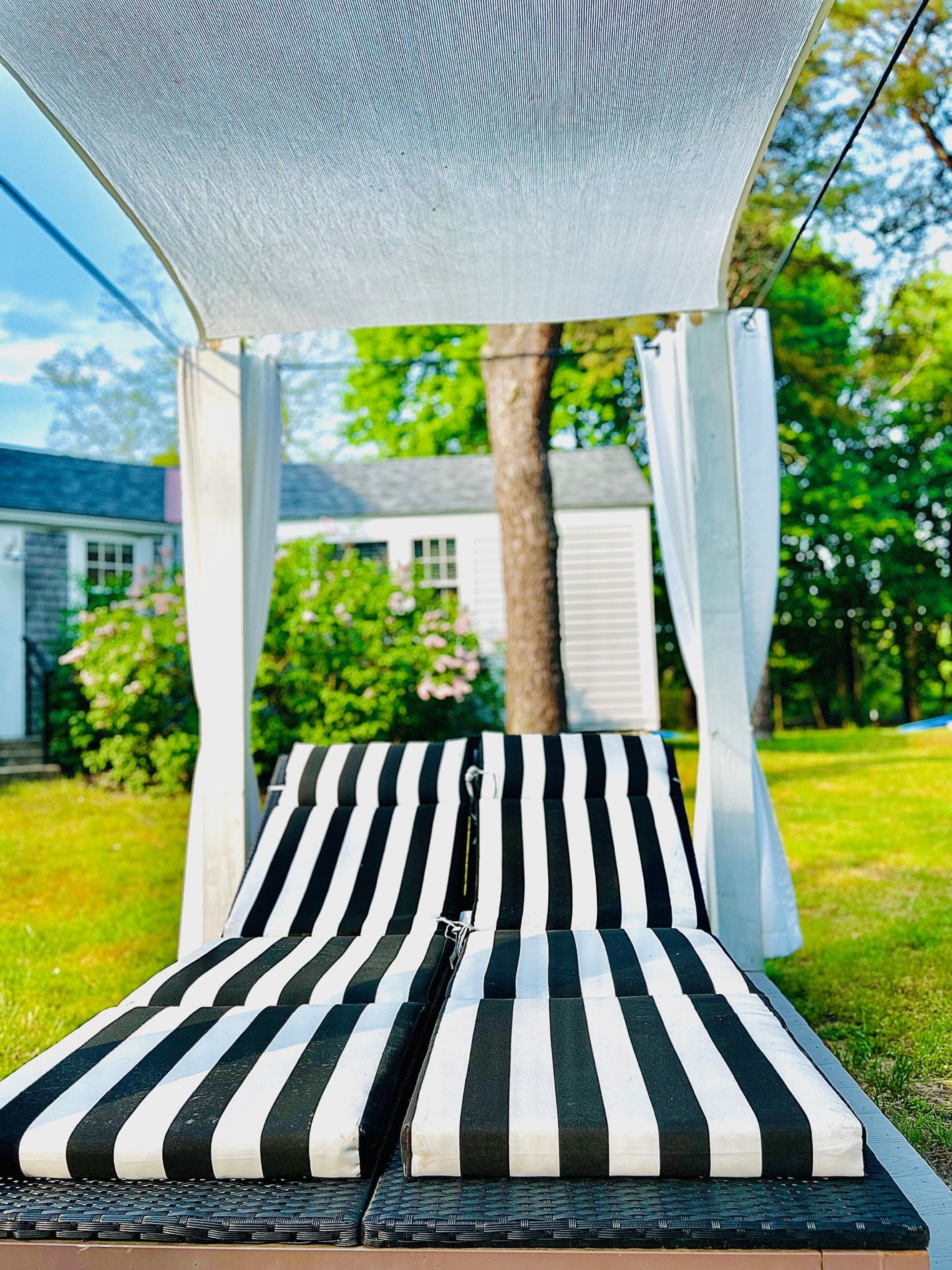 A lounge chair with a striped cushion under a white canopy.