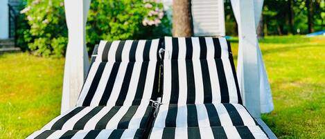 A lounge chair with a striped cushion under a white canopy.