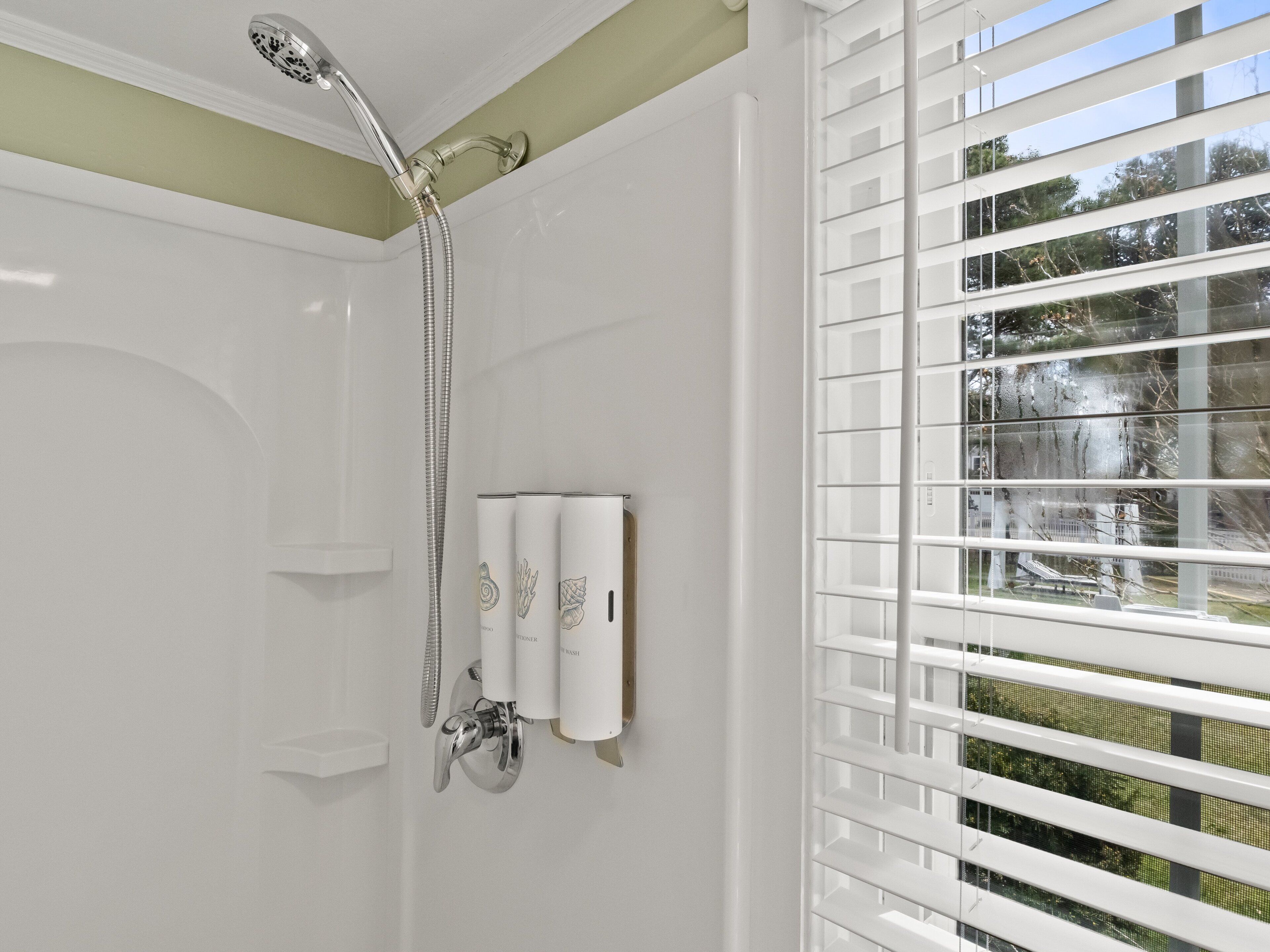 Ein modernes Badezimmer mit Dusche, Toilette und einem Fenster mit Jalousien.