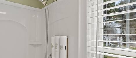 Ein modernes Badezimmer mit Dusche, Toilette und einem Fenster mit Jalousien.