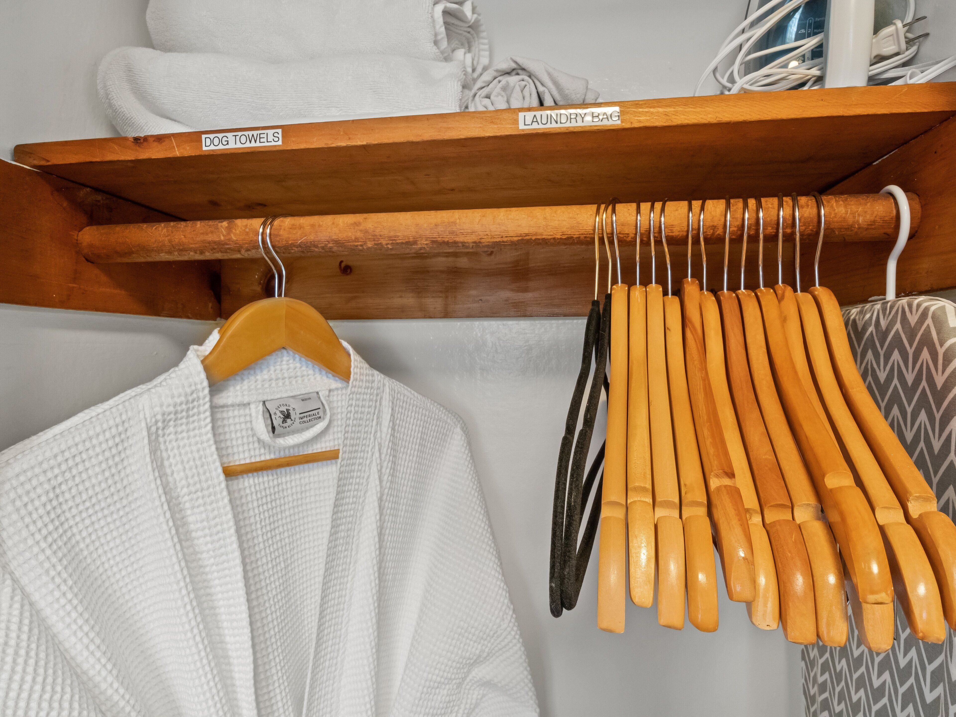 A wooden shelf with labeled hangers for dog towels and laundry bags.