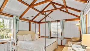 Um quarto espaçoso com uma cama grande, teto de madeira e janela com cortinas.