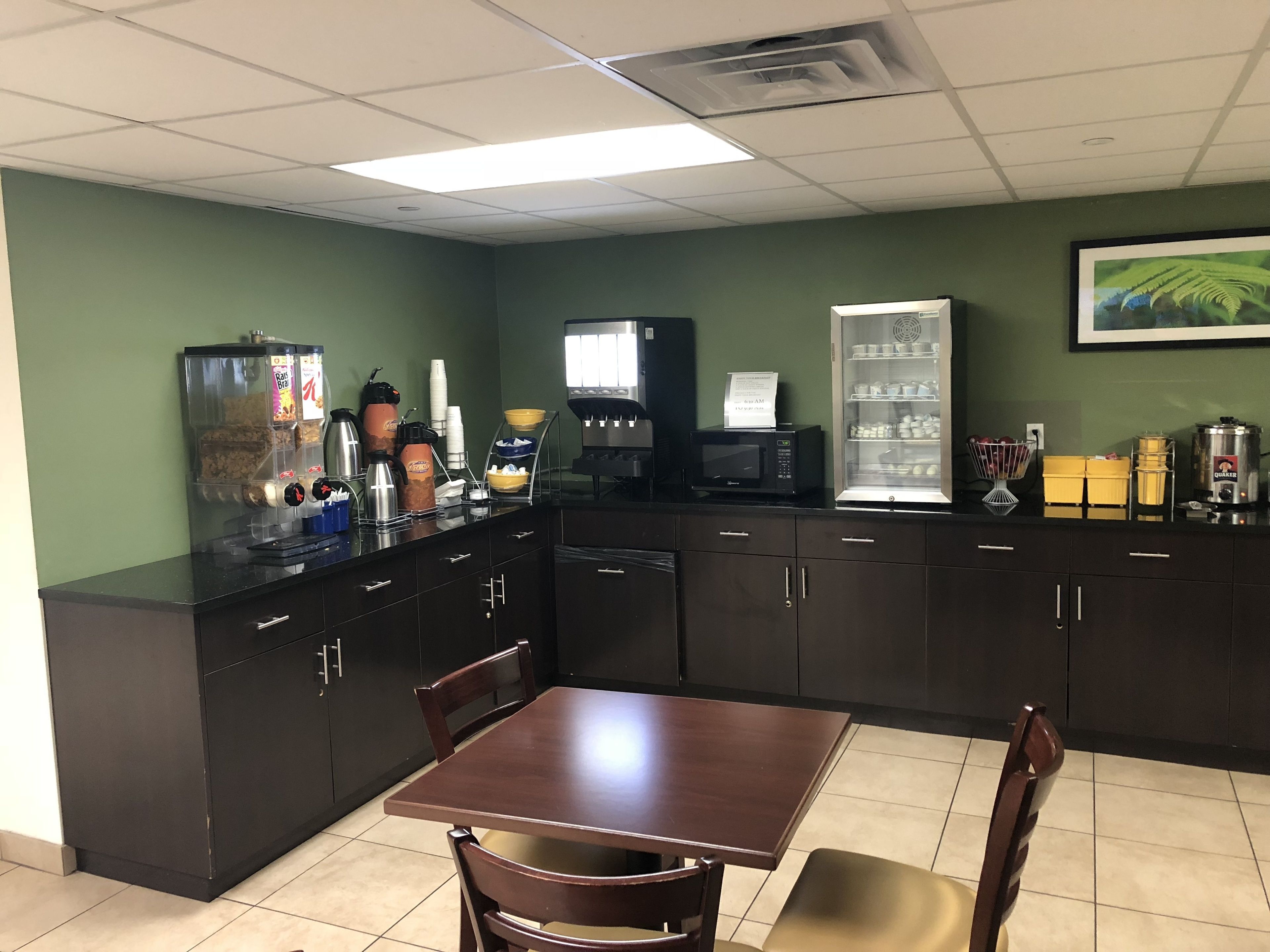 Uma cozinha com mesa e cadeiras, equipada com cafeteira, micro-ondas e frigorífico.