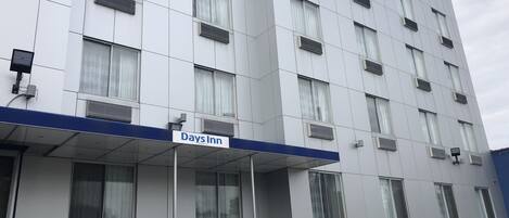 Un edificio Days Inn con fachada azul y blanca, varias ventanas y unidades de aire acondicionado.