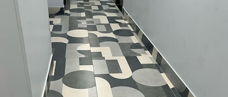 A hallway with a patterned floor, an exit sign, and a phone on the wall.