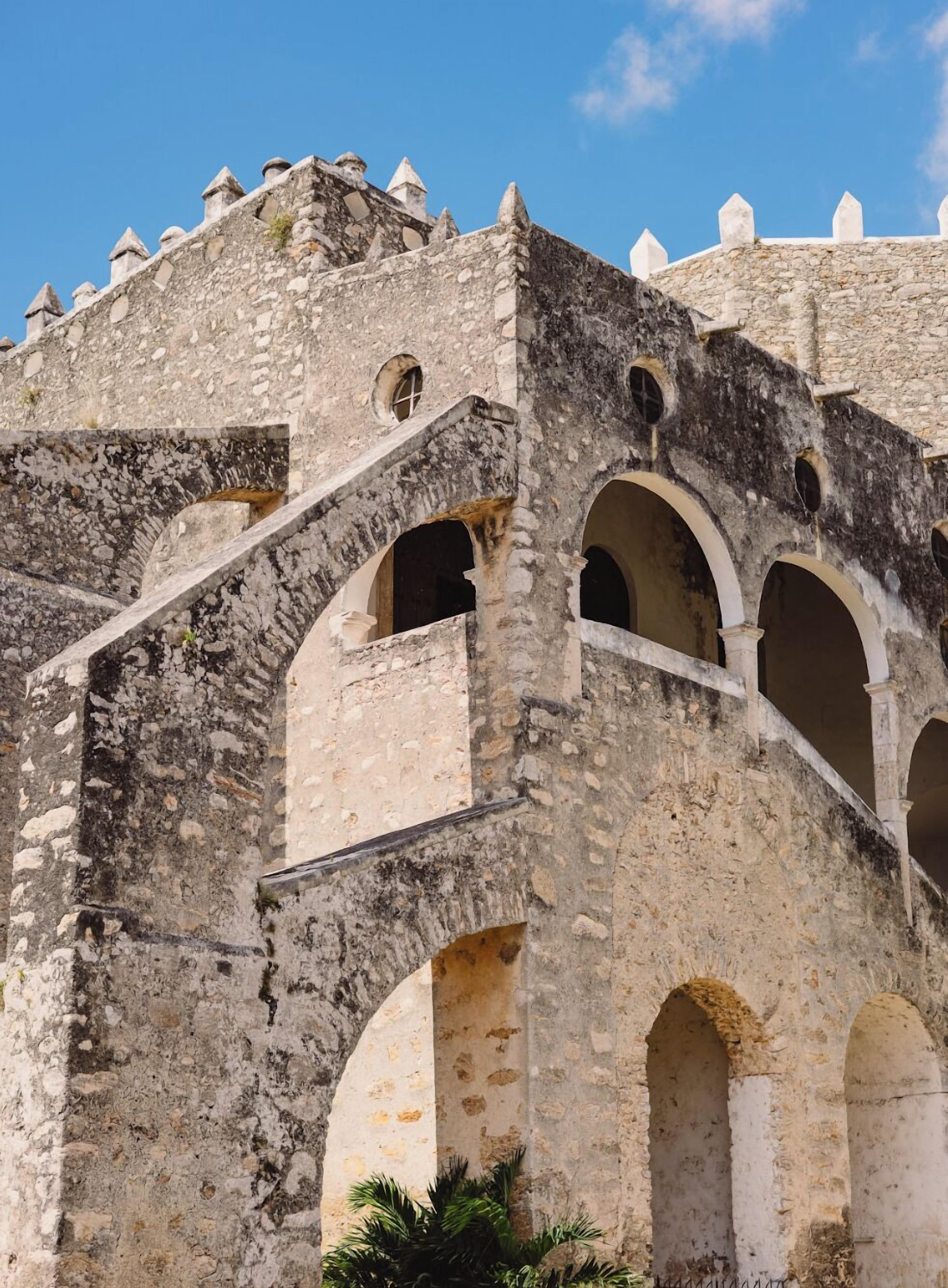Un edificio histórico de piedra con ventanas en arco y almenas.