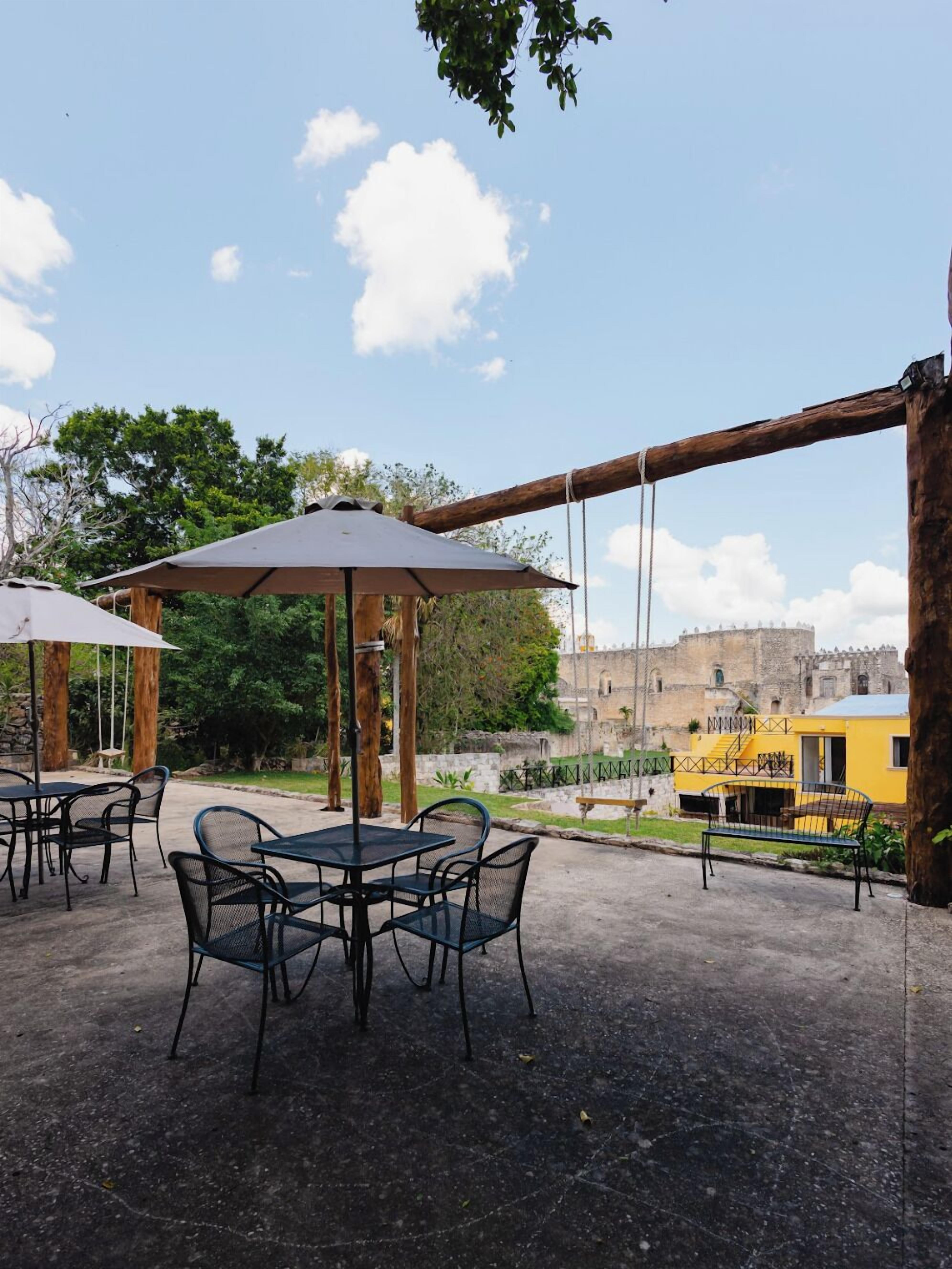 An outdoor patio with tables and chairs, a swing set, and a view of a historic building.