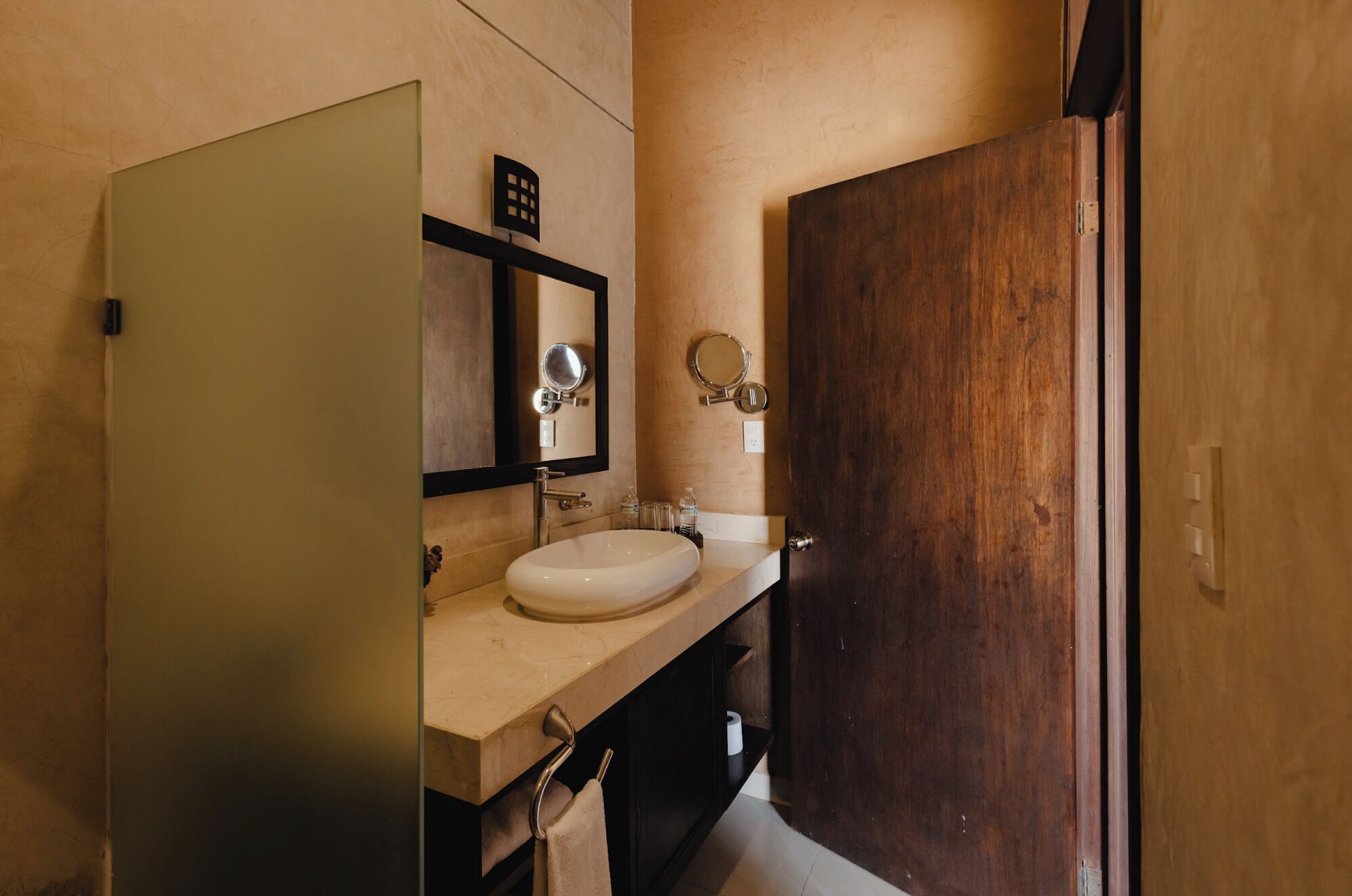 A bathroom with a white sink, a mirror, and a wooden door.
