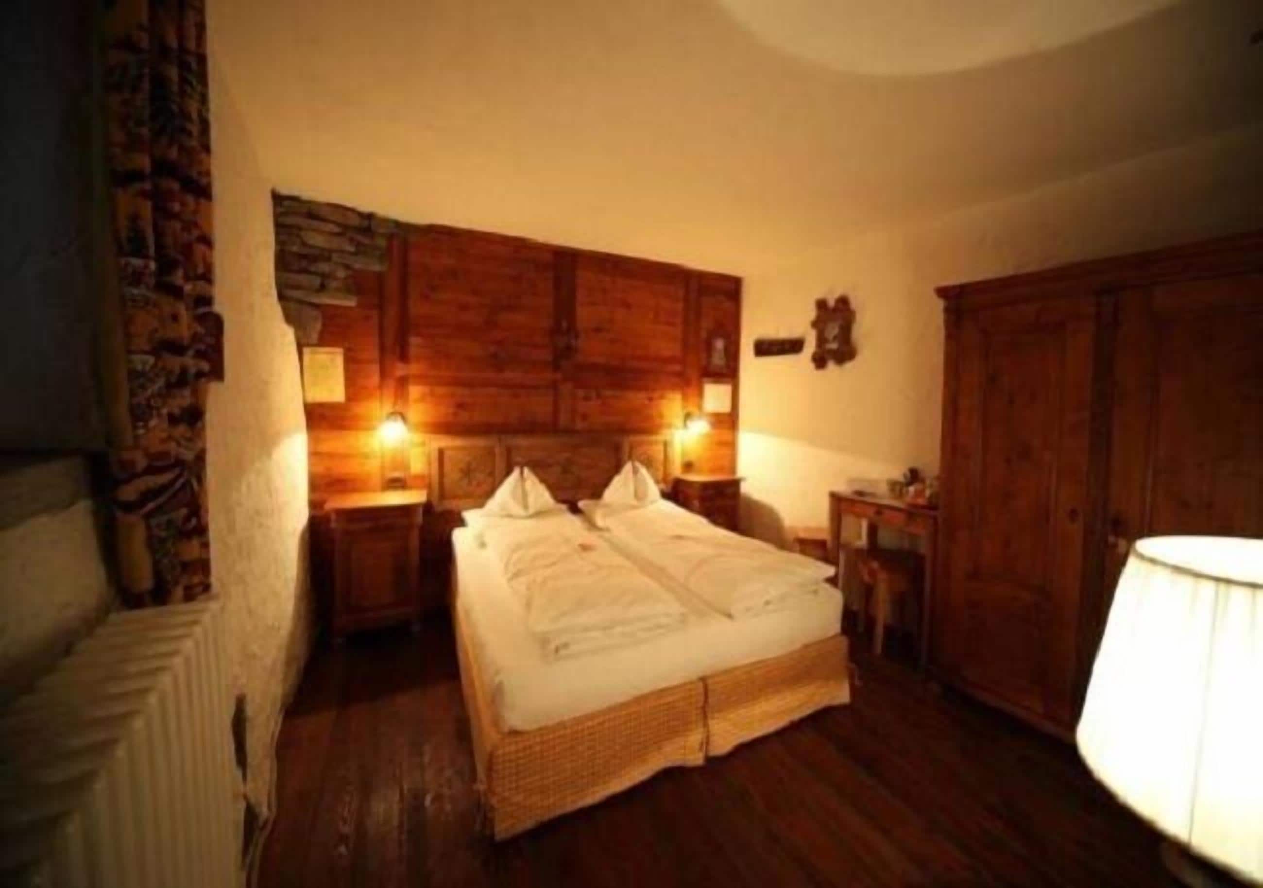 Ein gemütliches Zimmer mit einem großen Bett, einem hölzernen Kopfende und einer Steinwand.