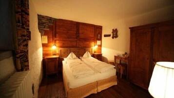 Una habitación acogedora con una cama grande, cabecero de madera y pared de piedra.