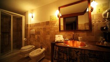 A bathroom with a shower, toilet, bidet, and a sink with a mirror above it.