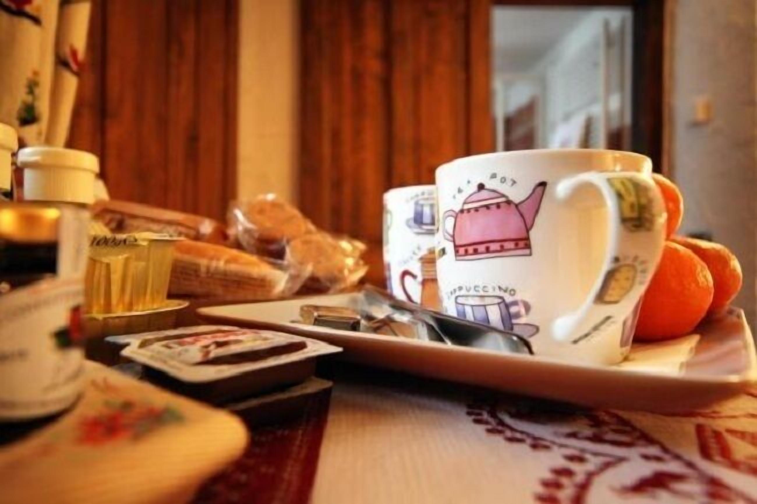 Een dienblad met een mok, een sinaasappel en een klein doosje, waarschijnlijk met thee of koffie, op een tafel met een geruit tafelkleed.