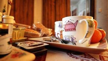 Een dienblad met een mok, een sinaasappel en een klein doosje, waarschijnlijk met thee of koffie, op een tafel met een geruit tafelkleed.