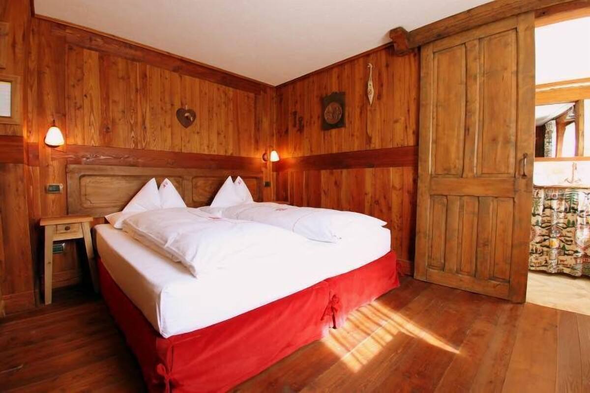 A wooden room with a bed, a nightstand, and a wardrobe.