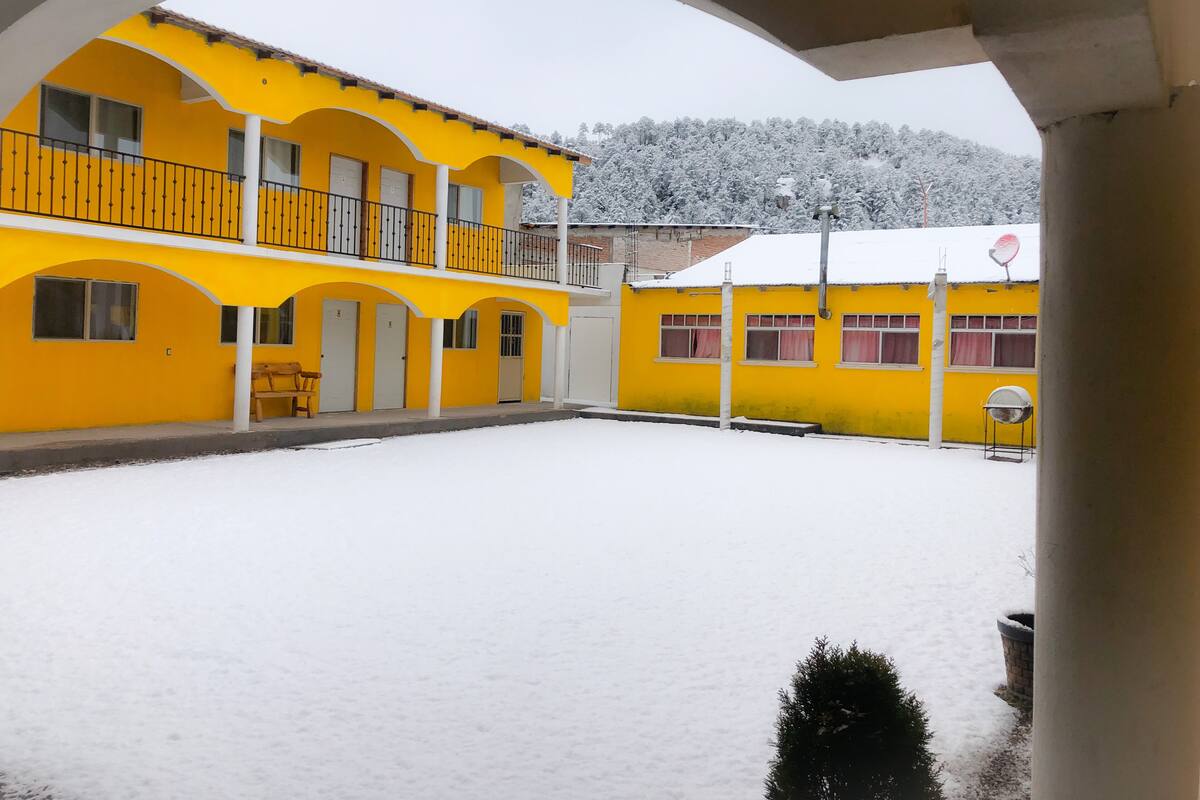 Ein gelbes Gebäude mit überdachtem Innenhof und verschneiter Landschaft.