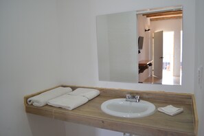 Un baño con tocador de madera, un lavabo blanco y un espejo.