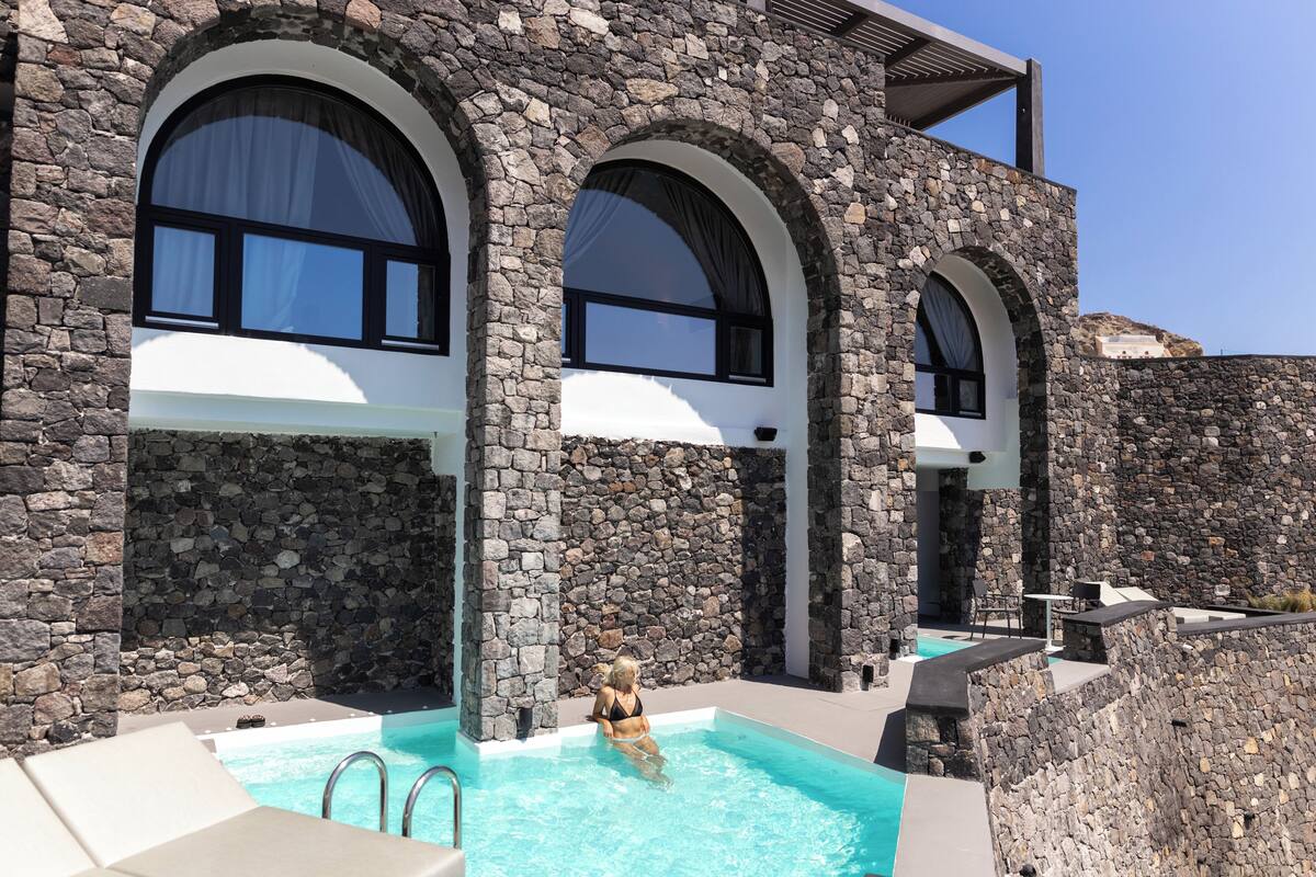 A stone building with a swimming pool and lounge area.