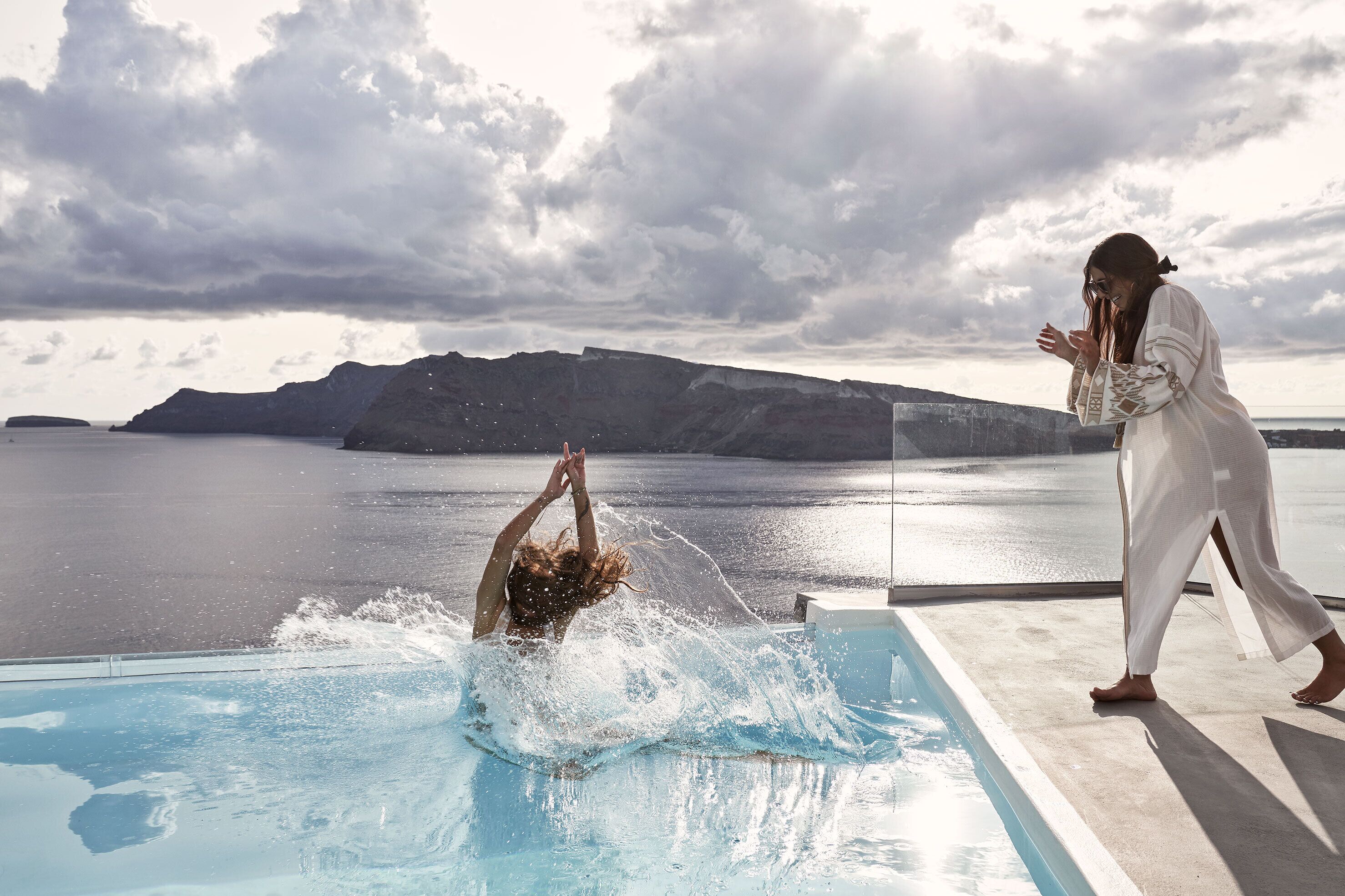 A person diving into a pool with a mountainous landscape in the background.