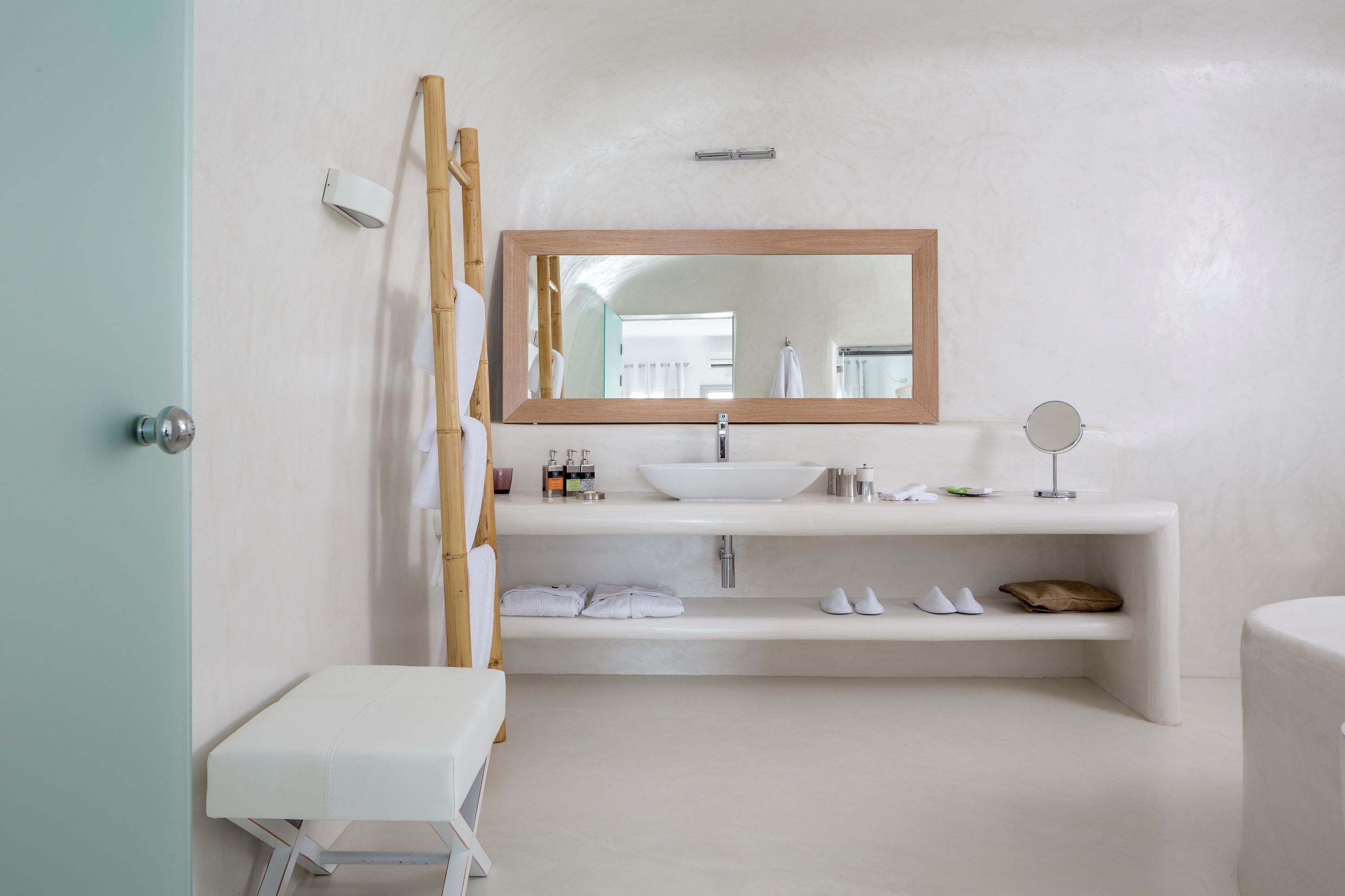 Un baño moderno con un espejo grande, lavamanos blanco y estantes integrados.